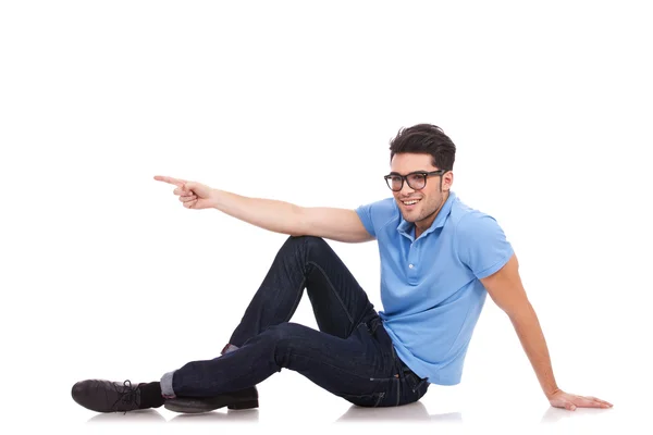 Homem casual sentado apontando para um lado — Fotografia de Stock