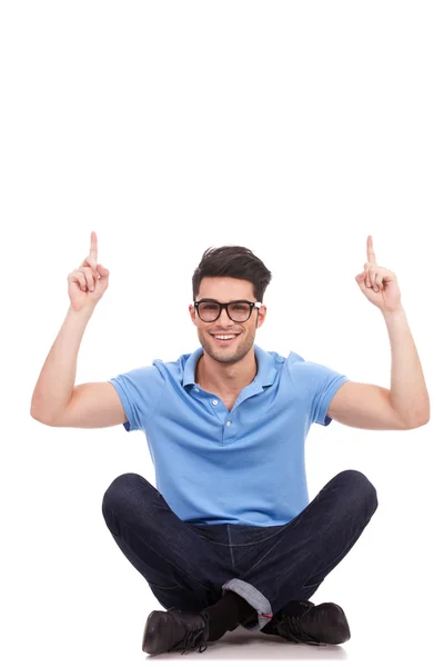 Homem casual sentado e apontando para cima — Fotografia de Stock