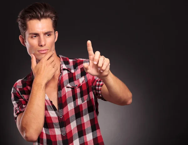 Pensativo hombre casual presionando en una pantalla en blanco imaginario — Foto de Stock