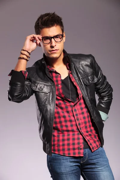 Man in leather jacket and jeans holding his glasses — Stock Photo, Image