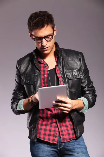 Young casual man with glasses working on tablet — Stock Photo, Image