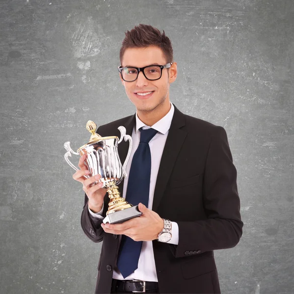 Business man with glasses holding a big trophy — Stock Photo, Image