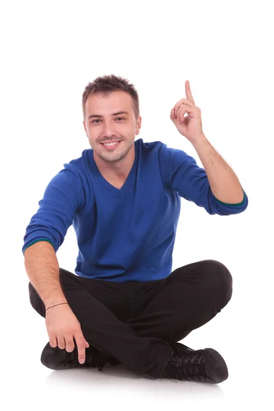 Jovem sentado casual homem apontando para cima — Fotografia de Stock