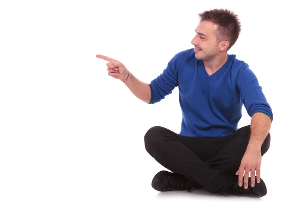 Man sitting on the floor and pointing to side — Stock Photo, Image