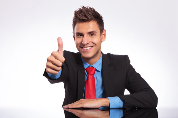 business man at desk showing thumb up