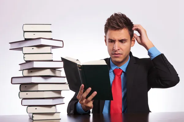 Confused man reading at desk — Stock Photo, Image