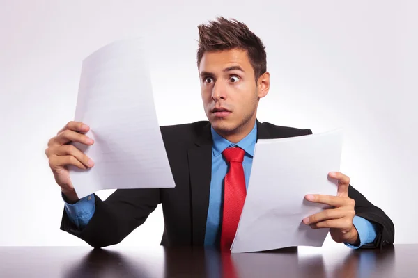 Überraschter Mann liest Brief am Schreibtisch Stockfoto