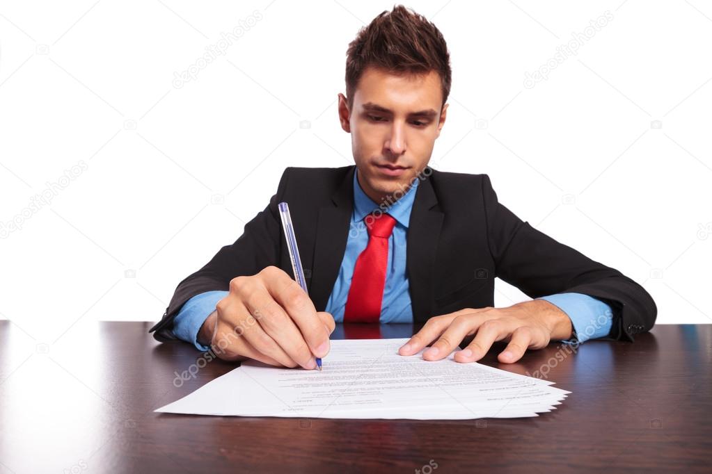 man writes at desk
