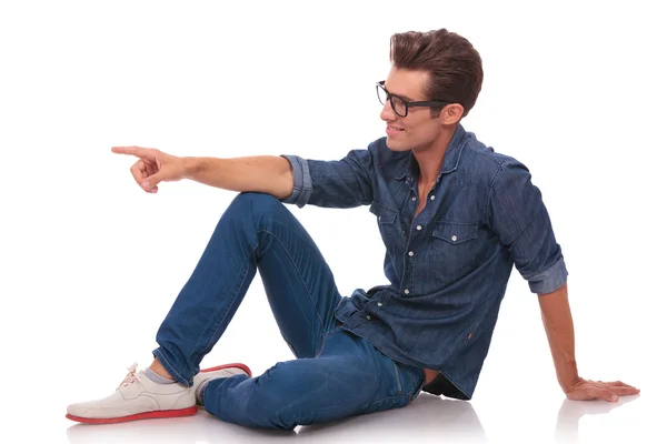 Seated man points to side — Stock Photo, Image