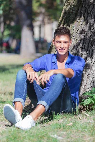 Hombre sonríe desde la base del árbol —  Fotos de Stock