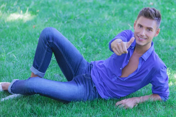 Young man on ground ok sign — Stock Photo, Image