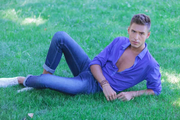 Ernstige jonge man rust in gras — Stockfoto