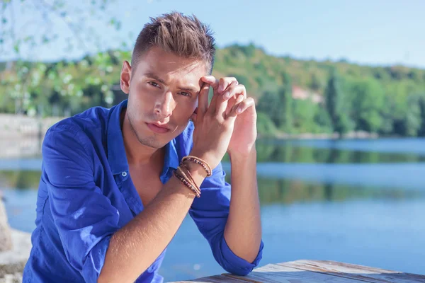 Homme posant à table près du lac — Photo