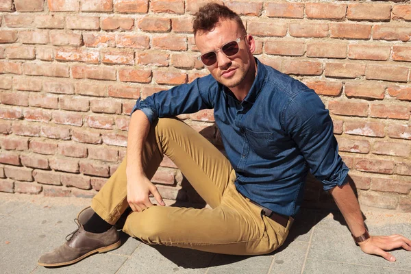 Casual man seated by brick wall — Stock Photo, Image