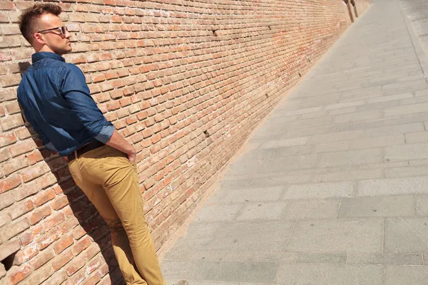 Casual man door muur met handen in zakken — Stockfoto