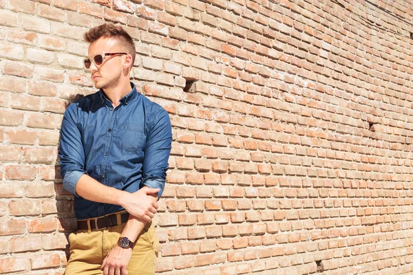 Casual man stands next to wall — Stock Photo, Image