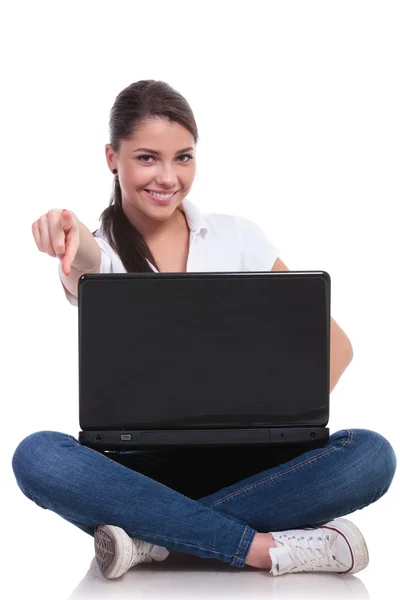 Casual woman sits with laptop & points Stock Image