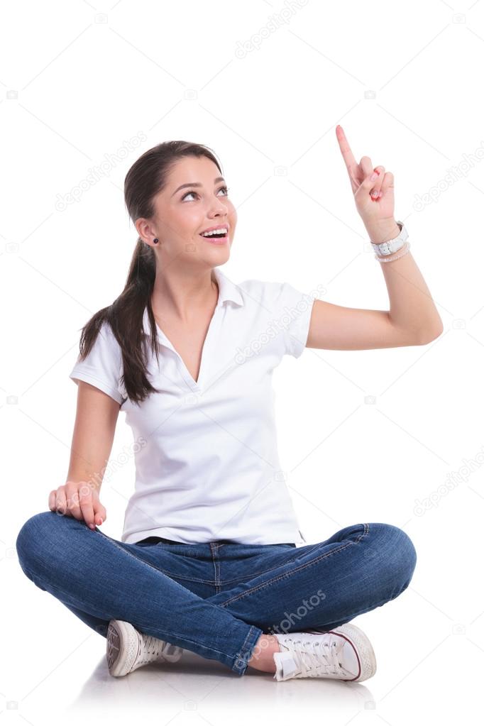 casual woman sits & points up
