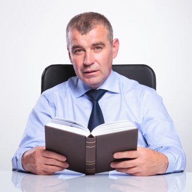 eski iş adamı bir kitap masasında tutuyor.