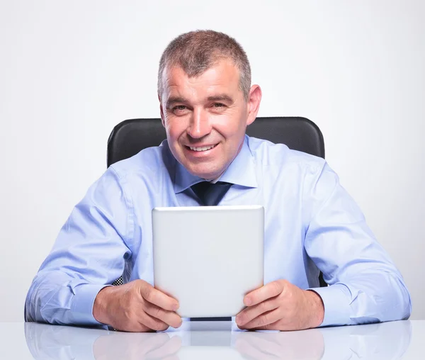 Alter Geschäftsmann am Schreibtisch hält sein Tablet — Stockfoto