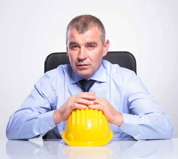 Old business man sits with hands on helmet — Stock Photo, Image