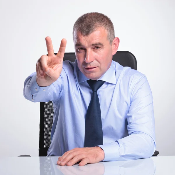Senior man shows victory from desk — Stock Photo, Image