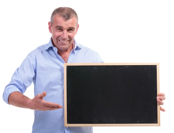 Lässiger Mann mittleren Alters zeigt auf Tafel — Stockfoto