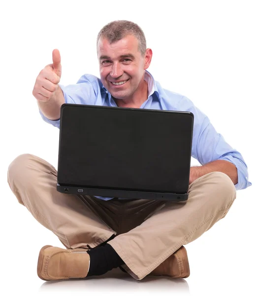 Casual old man sits with laptop and shows ok Royalty Free Stock Photos