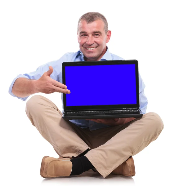 Casual old man sits and presents his laptop Royalty Free Stock Images