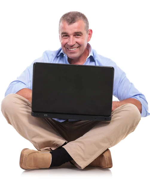Casual old man sits and works at laptop Stock Picture