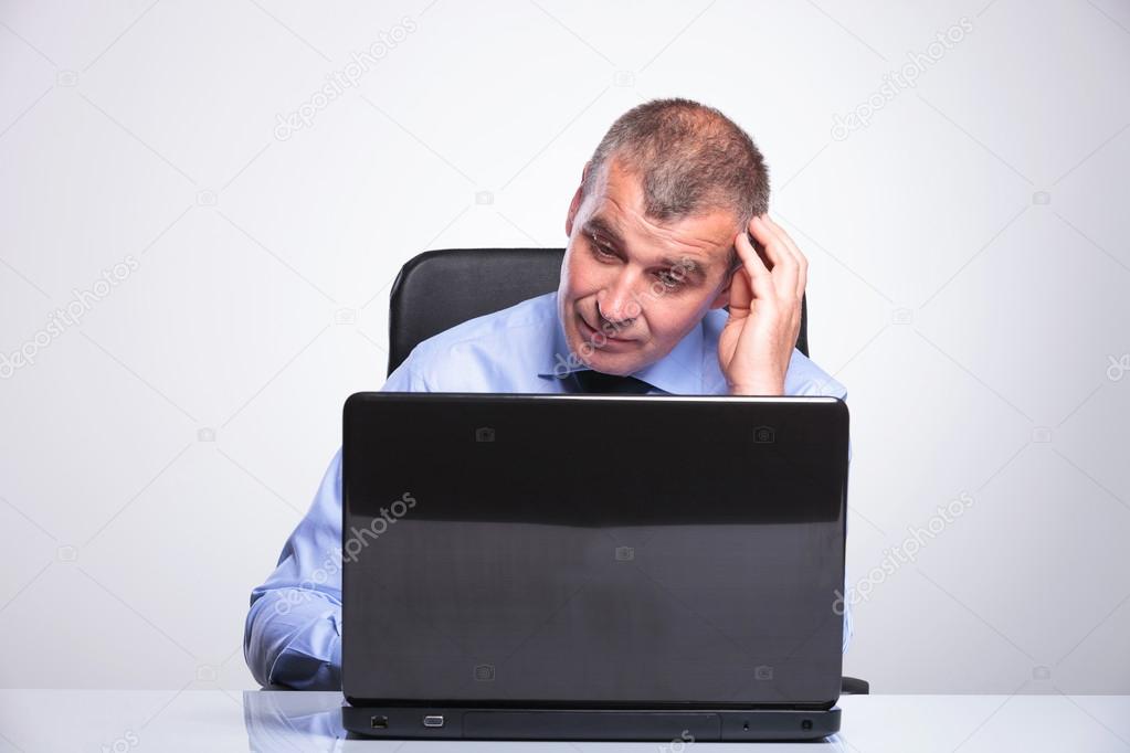 old business man looks puzzled at laptop