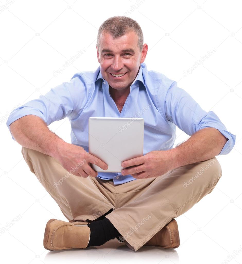 casual old man sits and holds tablet