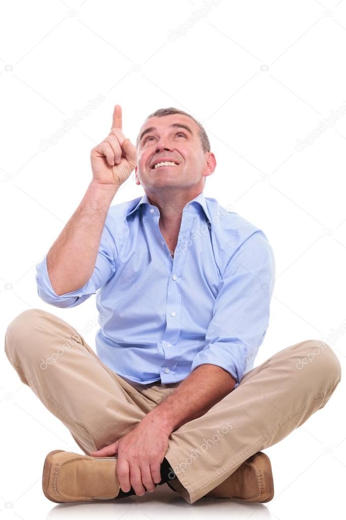 casual middle aged man sits and points up