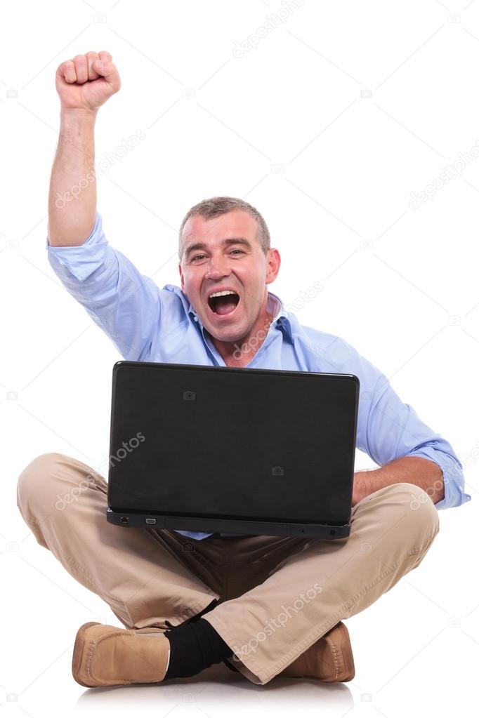casual old man sits and cheers with laptop