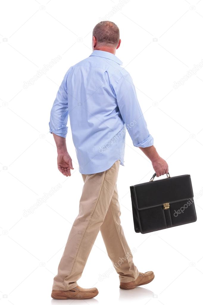 casual middle aged man walks with suitcase
