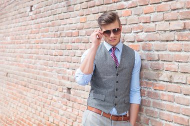 Casual adam duvara eğilir ve güneş gözlüğü ayarlamak