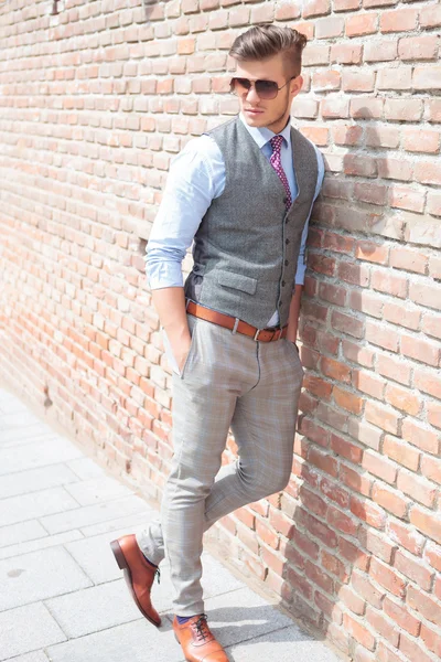 Casual man leans on a brick wall — Stock Photo, Image