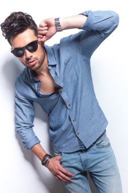 hombre casual con mano en gafas de sol