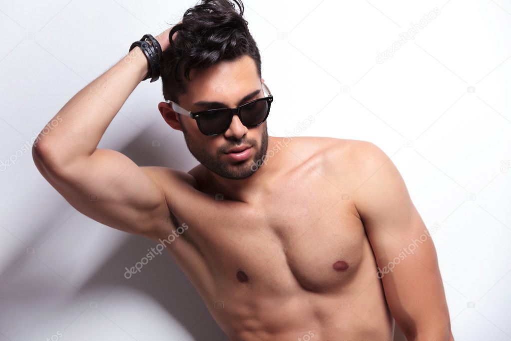 closeup of topless young man fixing his hair