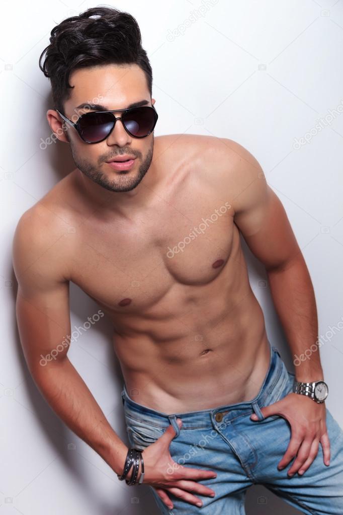 topless young man with thumbs in jeans loops