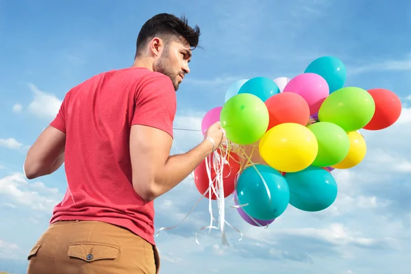 Achteraanzicht van casual man met ballonnen — Stockfoto