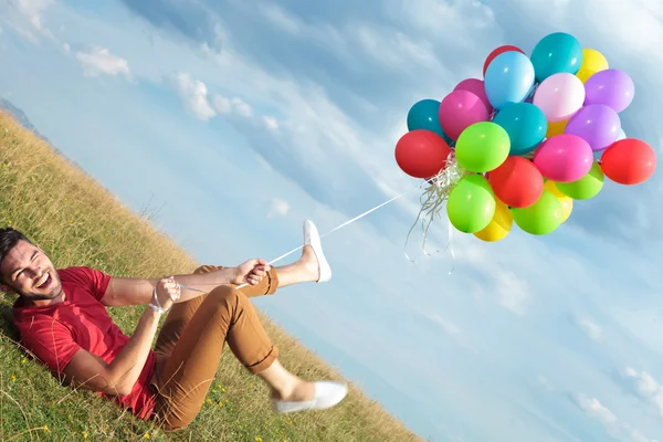 Homem casual no chão puxado por balões — Fotografia de Stock