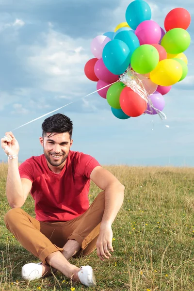 Casual man met een bos van ballonnen in zijn hand — Stockfoto