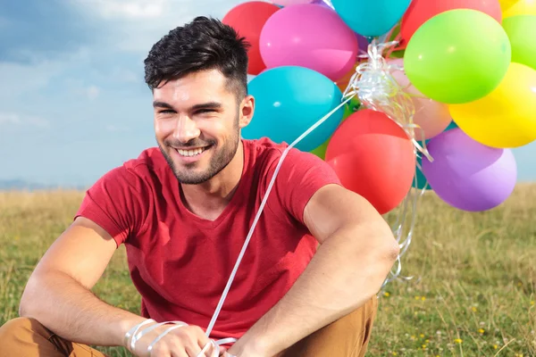 Closeup of seated casual man with balloons — Stock Photo, Image