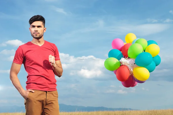 Příležitostné muž s balónky drží ruku v kapse — Stock fotografie
