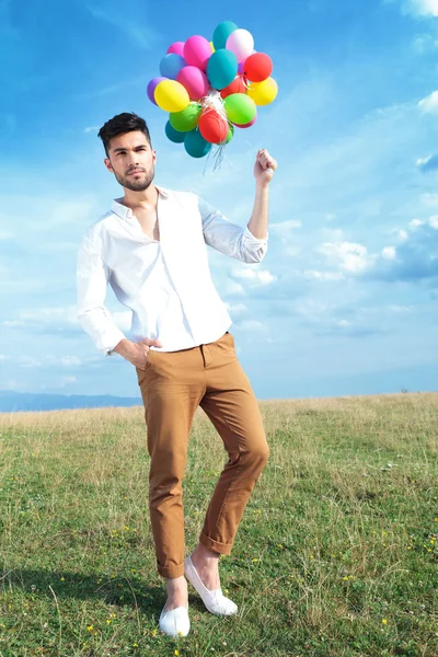 Casual man with balloons and hand in pocket — Stock Photo, Image