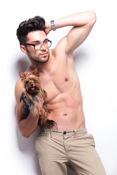 Topless joven hombre sostiene cachorro y fija el pelo — Foto de Stock
