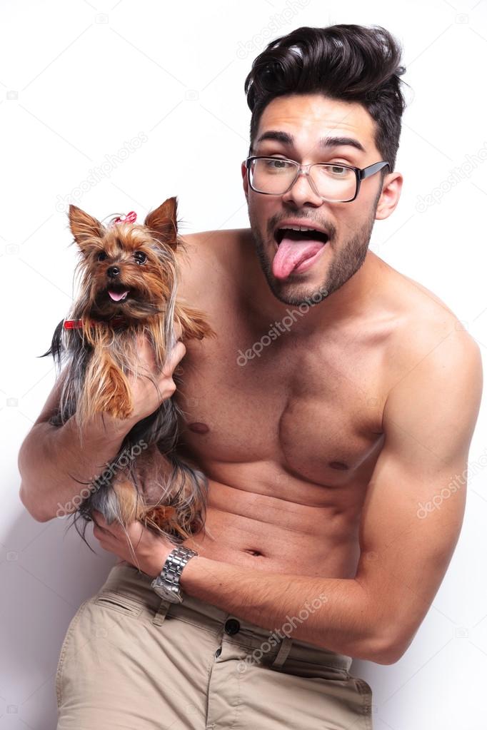 topless young man holding puppy and panting