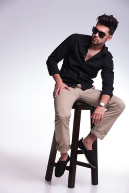 oturan genç adam kameradan uzak görünüyor.