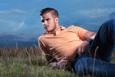 casual man laying in the grass and looking away clipart
